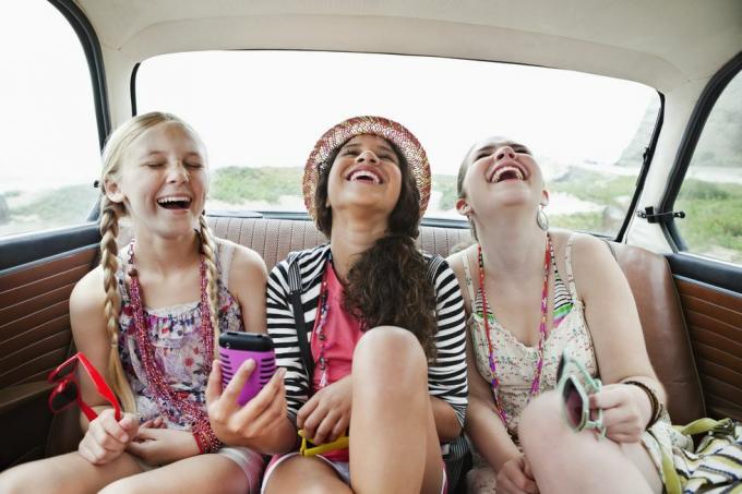 שלוש בנות צוחקות במושב האחורי של רכב