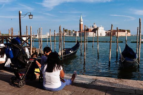 תיירים יושבים על הקרקע בוונציה כשהם משקיפים על כנסיית סן ג'ורג'יו