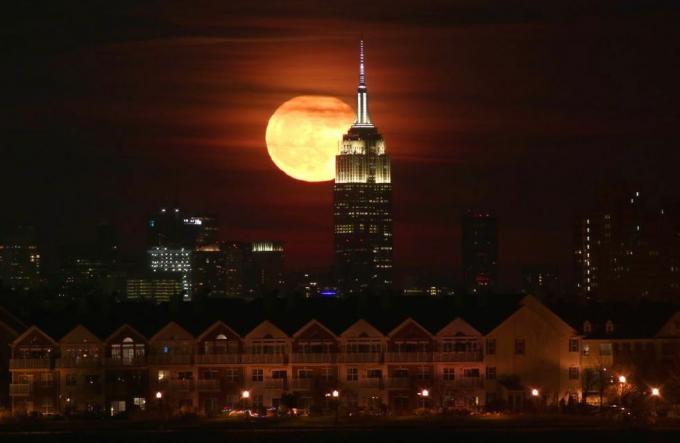 ירח מלא עולה מאחורי בניין האמפייר סטייט בניו יורק
