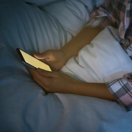 אישה משתמשת בסמארטפון במיטה בלילה, נומופוביה מקרוב והפרעות שינה