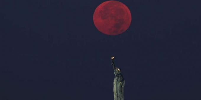ירח מלא שוקע מאחורי פסל החירות בניו יורק
