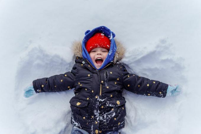 ילד צעיר בשלג עושה מלאך שלג