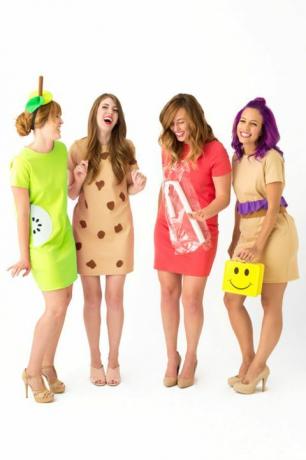 ארבע נשים צוחקות בשמלות קצרות לבושות "גבירות צהריים", אחת נושאת קופסת אוכל צהובה